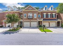 Brick townhomes with two-car garages, landscaped lawns, and a charming facade at 7524 Portbury Park Ln, Suwanee, GA 30024