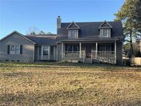 Charming two-story home featuring a cozy front porch and a well-maintained yard on a sunny day at 7977 Woods Ln, Jonesboro, GA 30236