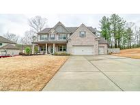 Charming two-story home with brick and siding exterior, attached garage, landscaped yard, and a welcoming front porch at 2106 Sycamore Ln, Loganville, GA 30052