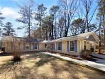 Charming ranch-style home featuring a brick facade, blue shutters, and a well-manicured front yard, all under a bright blue sky at 8005 Bamby Ln, Jonesboro, GA 30236