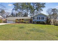 Charming blue two-story home with lush green lawn, mature trees, and attached two-car garage at 860 Valleymeade Se Dr, Marietta, GA 30067
