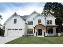Beautiful two-story home featuring a white brick and siding exterior with a two-car garage and a covered front porch at 1533 Grayson Pkwy, Grayson, GA 30017