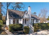 Charming white home featuring a manicured lawn, complemented by beautiful bushes at 1007 S Candler St, Decatur, GA 30030