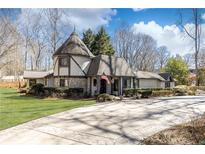 Charming Tudor style home featuring a turret and stone accents, set on a well-manicured lawn at 4210 Gatewood Ln, Peachtree Corners, GA 30097