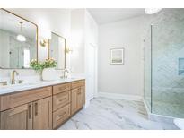Bright bathroom features double sinks, wood cabinets, modern fixtures, and glass enclosed shower with decorative tile at 1826 Terry Mill Se Rd, Atlanta, GA 30316