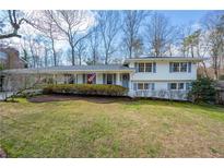 Charming white house with blue shutters, well-manicured lawn, and mature trees create a welcoming curb appeal at 165 Devonwood Dr, Sandy Springs, GA 30328
