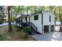 Charming home with a black and white exterior, landscaped yard and convenient two-car garage at 2450 Spring Mill Cv, Duluth, GA 30097
