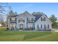 Charming two-story home with blue siding, well-manicured lawn, and meticulously landscaped flowerbeds at 2040 Winding Circle Trl, Fairburn, GA 30213