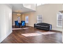 An open-concept living room with a tufted sofa, dining table, and hardwood floors, bathed in natural light at 409 Angier Ne Ct, Atlanta, GA 30312