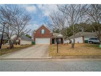 Charming single-Gathering home featuring a brick facade, well-manicured lawn, and attached two-car garage at 4932 Wilkins Station Dr, Decatur, GA 30035