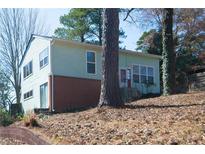 Charming home featuring a light green exterior, brick accents, and a welcoming red front door at 5087 Fairmont Se Rd, Smyrna, GA 30082