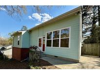 Light-green single-story home with large windows, red door, and a concrete path leading to the entrance at 5087 Fairmont Se Rd, Smyrna, GA 30082