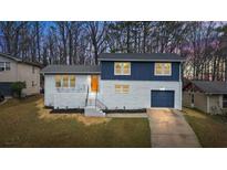 Charming two-story home featuring a white brick facade, blue accents, and a bright orange front door at 3565 Collier Drive Nw Rd, Atlanta, GA 30331