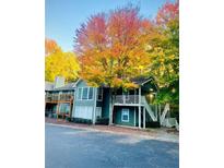 Inviting exterior view of a condo with stairs and a balcony surrounded by colorful fall trees at 810 Berkeley Woods Dr, Duluth, GA 30096