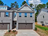 Two-story townhome with a painted brick facade, brown garage doors, and professionally landscaped yard at 5485 Rock Place Ct # 42, Norcross, GA 30093