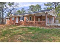 Charming brick home with a covered porch and carport, surrounded by mature trees and a well-maintained lawn at 2924 Vogue Dr, Douglasville, GA 30134