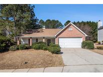 Charming one-story brick home featuring a two-car garage and mature landscaping at 11941 Fairway Overlook, Fayetteville, GA 30215