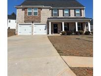 Two-story home featuring a two-car garage, brick facade, and a covered front porch with stately columns at 1367 Midnight Ride Ct, Hampton, GA 30228