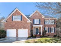 Charming brick two-story home with a two-car garage and lush front lawn and dark blue shutters at 2869 Amesbury Nw, Kennesaw, GA 30144