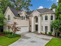 Stately home featuring a columned entryway and attached two-car garage, all surrounded by lush landscaping at 910 Renaissance Way, Roswell, GA 30076