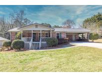 Charming brick home with covered carport, manicured lawn, and inviting front porch at 4031 Pine Needle Dr, Duluth, GA 30096