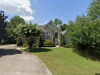 Charming home with a manicured lawn, mature trees, and a circular driveway creating a welcoming curb appeal at 8925 Nesbit Lakes Dr, Alpharetta, GA 30022
