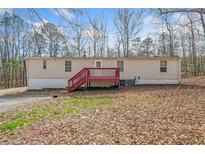 Backyard with a red deck, neutral siding, mature trees, and a level lot at 95 Riverbrooke Trl, Covington, GA 30016