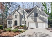 Stately stucco home featuring a manicured lawn, attached two car garage and mature landscaping at 313 Calla Ln, Alpharetta, GA 30005