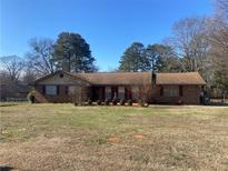 Charming single-story brick home with a well-manicured front yard and mature trees at 1655 Old Salem Rd, Covington, GA 30013