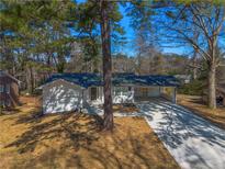 Charming single-story home with a long driveway and attached carport, surrounded by mature trees at 1890 Carla Dr, Morrow, GA 30260