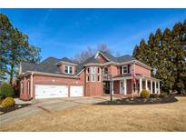 Stately brick home featuring a two-car garage, manicured lawn, and covered front porch at 1605 Ridge Haven Run, Alpharetta, GA 30022