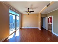 Bright living room featuring hardwood floors, a ceiling fan, and a sliding glass door to a balcony with city views at 2626 Peachtree Nw Rd # 1007, Atlanta, GA 30305