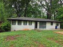 Ranch style home with white painted brick and dark trim, surrounded by mature trees at 3490 Primrose Pl, Decatur, GA 30032