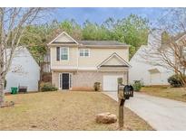 Charming two-story home featuring a well-manicured lawn and a one car garage at 6797 Mahonia Pl, Lithonia, GA 30038