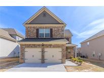 Two-story brick home featuring an attached two-car garage and a well-maintained front yard at 7434 Rudder Cir, Fairburn, GA 30213
