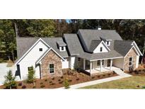 Beautiful single-Gathering home featuring stone and vinyl siding, a spacious front porch, and manicured landscaping at 110 Farr Lake Dr, Tyrone, GA 30290