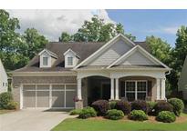 Charming brick home with a covered front porch, manicured lawn, and two-car garage, nestled among mature trees at 131 Riverside Ln, Woodstock, GA 30188