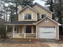 Two-story home with siding, a covered front porch, an attached garage, and white trim at 5396 Kirk Dr, Atlanta, GA 30349