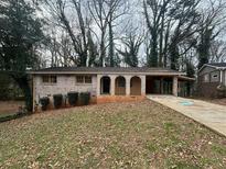 Charming brick home featuring an arched entryway, an attached carport, and a spacious front yard at 612 San Pablo Ct, Stone Mountain, GA 30083