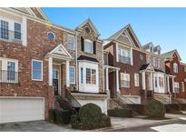 Attractive townhome row with brick facade, multiple stories, and well-manicured landscaping under a clear blue sky at 1286 Creekside Se Ter, Smyrna, GA 30082