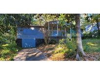 Blue single-Gathering home with covered porch, boarded windows, and overgrown landscaping needs renovation at 1775 Hadlock Sw St, Atlanta, GA 30311