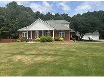 Charming brick home with a manicured lawn, columns, and a well-maintained landscape at 3220 Indian Shoals Rd, Dacula, GA 30019