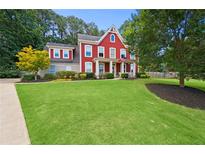 Charming two-story home with a well-manicured lawn, landscaping, and an inviting front porch at 3460 Trow Creek Ln, Cumming, GA 30040