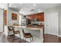Modern kitchen features a marble countertop breakfast bar, stainless steel appliances, and sleek dark wood cabinets at 565 Peachtree St # 1311, Atlanta, GA 30308