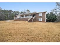 Charming brick home features a covered front porch and mature trees on a spacious lawn at 6069 Shallow Wood Ln, Douglasville, GA 30135