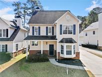 Charming two-story home with beige siding, a dark roof, and blue shutters, all surrounded by mature trees at 3302 Heritage Walk Ln, Duluth, GA 30096