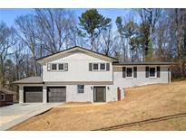 Two-story home featuring a light-painted brick facade, dark shutters, and a two-car garage with a driveway at 3001 W Potomac Dr, Atlanta, GA 30344