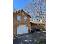 Charming brown home with a white garage door and covered porch at 1690 Eaglecreek Trl, Cumming, GA 30041