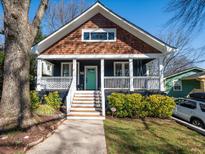 Charming home featuring a welcoming front porch with a teal front door and manicured landscaping at 1216 Mortimer Se Pl, Atlanta, GA 30317