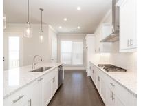 Modern kitchen featuring white cabinetry, granite countertops, stainless steel appliances and dark hardwood floors at 167 Basil Street, Cumming, GA 30040